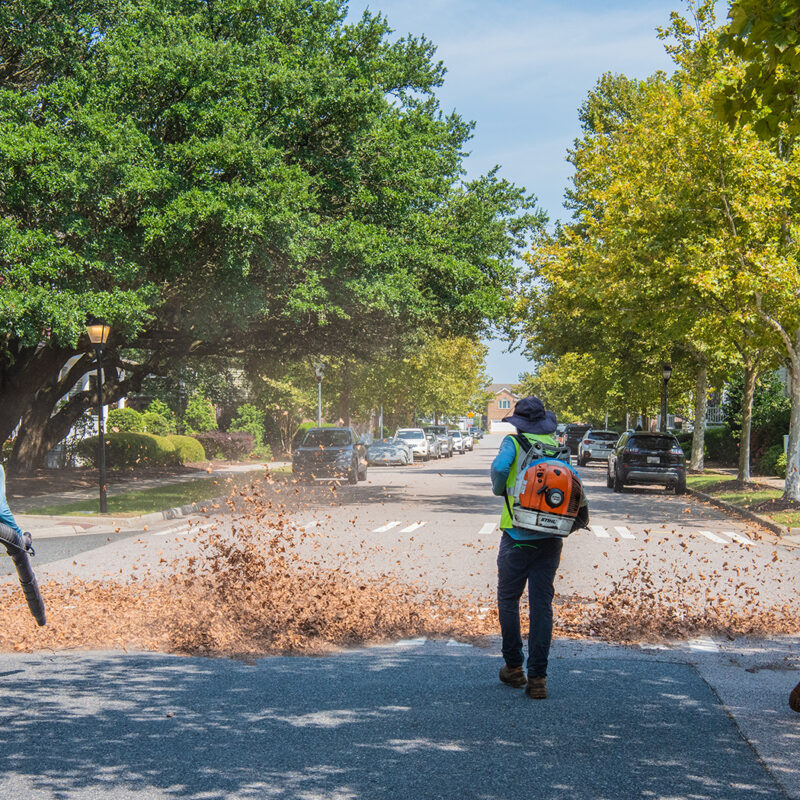 U.S. Lawns employees blowing leaves