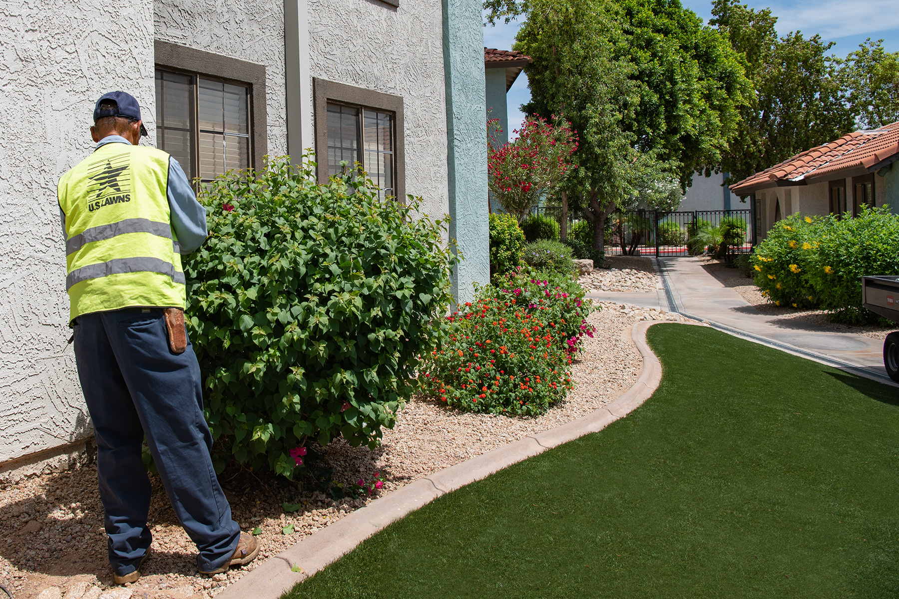 Commercial grounds maintenance technician servicing shrubs and rock landscape in the Phoenix metro area